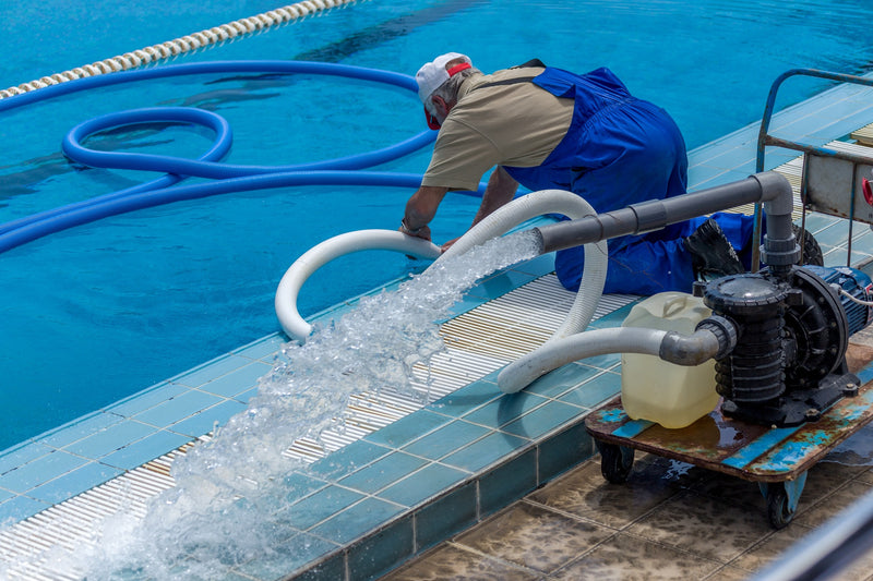 Person working on pool equipment by a swimming pool